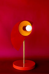 The Kin lamp by Sazerac Stitches is a sculptural masterpiece featuring powder-coated steel in vibrant red, orange peel, and oxblood tones. Its flame-colored base and brass details add a modern and artistic touch to any space.