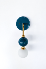 A statement wall sconce for rooms that lead with deep, saturated color. This angle of the Ida sconce shows off the bold round teal backplate along with the brass arm curving down to a glossy teal sphere and frosted glass globe. Petrol-rich and quietly confident, it's a sophisticated pick for colorful bathrooms, powder rooms, bedrooms, and eclectic spaces that want one soulful, standout detail.