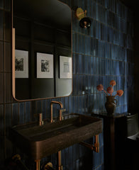 Black and brass mid century modern inspired wall sconce in a navy blue modern tile bathroom