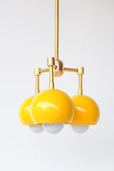 retro mid century inspired pendant light with three lights. Small brass and yellow pendant light fixture