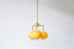 retro mid century inspired pendant light with three lights. Small brass and yellow pendant light fixture