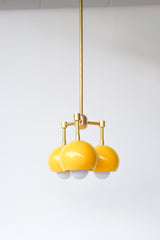 retro mid century inspired pendant light with three lights. Small brass and yellow pendant light fixture