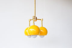 retro mid century inspired pendant light with three lights. Small brass and yellow pendant light fixture