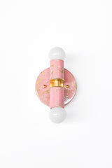 Side-angle detail of a pair of marbled Thalia sconces in blush pink, cream, and gold, showing how each hand-marbled pattern varies from piece to piece. The angled view emphasizes projection and the sculptural “totem” shape, with warm brass details and globe bulbs for a clean, modern finish. Perfect for flanking a mirror, framing a doorway, or adding personality to a small bathroom or hallway without overwhelming the space. A strong fit for eclectic design, pastel interiors, soft maximalism, and boutique-hot