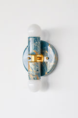 Thalia Sconce shown from an angled view highlighting the round wall plate, brass center band, and glossy lagoon, cream, and gold marbled discs. Two-light wall sconce or flush mount ceiling light designed for compact spaces and high-impact modern color.