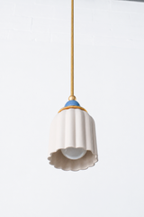 unglazed cream porcelain shade with blue and brass accents. the pendant shade has a ribbed shape and unglazed. Includes a powdercoated ball and brass hardware accents. Modern and handmade in New Orleans by Sazerac Stitches.