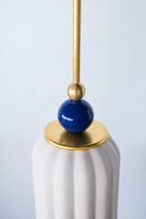unglazed cream porcelain shade with navy blue and brass accents. the pendant shade has a ribbed shape and unglazed. Includes a powdercoated  navy ball and brass hardware accents. Modern and handmade in New Orleans by Sazerac Stitches.