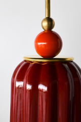 Rich, jewel tone red ceramic ceiling pendant with brass hardware and a flame orange powdercoated ball. Inspired by art deco glass with updated modern accents. This beautiful pendant light adds color and shape to any space. 
