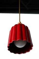 Rich, jewel tone red ceramic ceiling pendant with brass hardware and a cream powdercoated ball. Inspired by art deco glass with updated modern accents. This beautiful pendant light adds color and shape to any space. 
