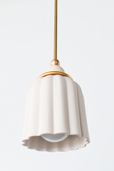 unglazed cream porcelain shade with cream and brass accents. the pendant shade has a ribbed shape and unglazed. Includes a powdercoated ball and brass hardware accents. Modern and handmade in New Orleans by Sazerac Stitches.