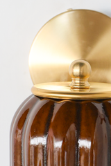 A closer look at the construction behind this handmade pottery sconce: a brass arm meets a ball finial and ring collar before the art deco fluted shade begins, its celadon-style glaze pooling rich chocolate brown down every groove. Small-batch, one-of-a-kind, and built to bring feminine, jewel-toned warmth to a colorful bathroom or serve as ambient lighting in a larger room.