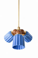 A blue and brown chandelier with a rich, moody edge that skips the expected pastel palette. The Marcella Small Chandelier is built from three fluted, scalloped ceramic shades in glossy sky blue, each attached at a round brass collar and flaring into a wavy, bell-shaped hem, arranged around a central cluster of chocolate brown glass globe bulbs on a brass stem. A grounded color pairing that works in a study, dining room, or any space that wants color with some depth.
