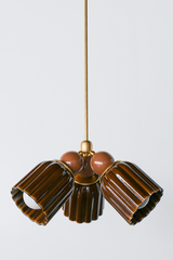 A small chandelier with glossy, glazed fluted ceramic cone shades in chicory brown, paired with fudge brown powder-coated steel balls and brass hardware. The glaze catches real shine across the fluting, giving this a richer, warmer feel than a matte finish. Two close tones of brown keep the fixture cohesive rather than contrasting, a strong fit for a cozy dining room, a library, or any space leaning warm and old-house rather than bright or coastal.