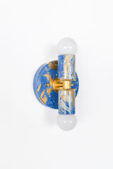 The Thalia sconce shown in a Mediterranean Blue marbled colorway with creamy veining and gold accents. Handmade and highly dimensional, it reads like functional wall art for bathrooms, hallways, bedrooms, or a statement powder room.