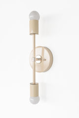 Straight on product photo of the Medium Thalia sconce in cream with chrome accents, a vertical double bulb wall sconce with exposed globe bulbs, a round backplate, and a sleek modern silhouette for mid century modern, contemporary, and minimal interiors