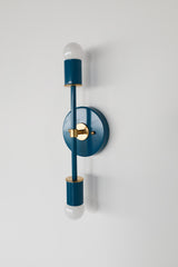Angled product photo of the Medium Thalia Sconce in Lagoon blue with warm brass accents. The two-light vertical design keeps the profile narrow while adding bold color, making it useful for small bathrooms, colorful powder rooms, bathroom mirrors, bedside lighting, hallway lighting, and playful modern or grandmillennial interiors.