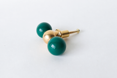 A double-ball drawer pull pairing two glossy mermaid green spheres with a polished brass ball at the center, shown at an angle to show its full shape. A teal-leaning green that works well in a coastal bathroom, a jewel-toned kitchen, or anywhere that wants saturated color without going fully emerald.