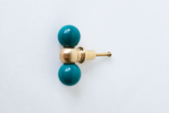 A closer, head-on look at the mermaid green and brass double-ball drawer pull, showing the brass center ball and glossy finish in detail. Useful for checking the exact shade and proportions before installing. Pretty colorful hardware that can match wallpaper in a colorful bathroom or space.  Adds personality to any boring cabinet or piece of furniture