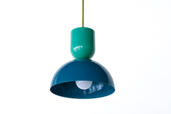 Color-blocking isn't just for walls, and this two-tone Taeuber pendant proves it. The sculptural silhouette pairs a glossy mermaid green cup top with a deep lagoon blue dome, joined by a warm brass stem, so you get two saturated jewel tones in one fixture. It reads bold, playful, and very custom, the kind of statement lighting that turns a kitchen island, breakfast nook, or bar into a real focal point. Hang one for a hit of unexpected color or a row for maximum impact. A great choice for a maximalist, colle