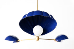 Close-up of a coastal Art Deco chandelier, featuring fluted navy blue shades and a central white bulb with brass detailing—perfectly suited for a Nancy Meyers-inspired aesthetic