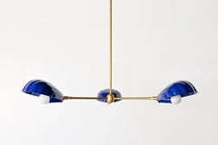 Close-up of a coastal Art Deco chandelier, featuring fluted navy blue shades and a central white bulb with brass detailing—perfectly suited for a Nancy Meyers-inspired aesthetic