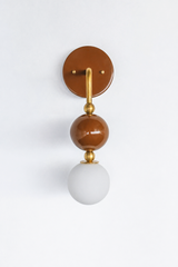 A statement wall sconce for rooms that lead with warm, saturated color. Seen in profile, the Ida sconce pairs a glossy chocolate-brown powder-coated sphere with a frosted glass globe, joined by warm brass hardware and a round brown backplate. Deep, cozy, and quietly confident, it's a spirited pick for moody bathrooms, powder rooms, bedrooms, and organic modern rooms that want one warm, standout detail.