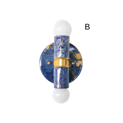 A hand-marbled blue Thalia sconce with deep navy tones, brighter blue swirls, and warm gold accents. The round backplate and cylindrical center create a simple geometric shape, while the marbling adds movement and personality. This blue wall sconce would work beautifully in a bathroom, powder room, or colorful space that leans coastal, eclectic, or bold.