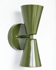 A warm, earthy double-cone wall sconce for a hallway, library, bar, or mid-century modern room that wants grounded color and crisp, two-directional light. The Dryades sconce pairs an upward and a downward olive-green cone at a narrow waist, mounted on a round olive backplate with a brass screw accent. Seen from an angle, its bowtie silhouette and wall projection read rich and a little retro — a confident pick for 70s-inspired, organic modern, and moody traditional spaces.