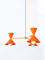 Bright orange is the color that instantly warms up a room and makes it feel fun, and this monochromatic Clancy chandelier commits all the way, shades, arms, and stem in one glossy orange peel. Three double-cone bowtie shades radiate from a central sphere hub in a crisp Italian-inspired mid-century silhouette, throwing light up and down from each arm. It's built to be the star over a dining table, kitchen island, or entry, the kind of statement piece that makes people ask whose house this is. Punchy, sculptu