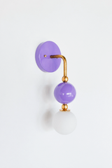A saturated orchid wall sconce for a girl's bathroom, bedroom, or playful powder room that leads with joyful color. The Ida sconce stacks a glossy purple powder-coated sphere over a frosted glass globe, joined by warm brass hardware and a round purple backplate. Bold and cheerful without tipping into childish, it's a standout for grandmillennial, maximalist, and colorful traditional homes that skip the safe answer.