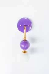 Bold, playful vanity lighting that gives a bathroom, powder room, or girl's bedroom real personality. Seen in profile, the Ida sconce shows off its curved brass arm reaching from a glossy orchid-purple backplate down to a stacked purple sphere and frosted glass globe. The side view highlights the brass ball detailing and how far the fixture projects off the wall. A fearless, saturated choice for maximalist, eclectic, and grandmillennial interiors.