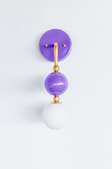 A statement wall sconce for rooms that lead with fearless color. This angle of the Ida sconce puts the bold round orchid-purple backplate front and center, with a brass arm curving down to a glossy purple sphere and frosted glass globe. Saturated, joyful, and unapologetically purple, it's a playful pick for girls' bedrooms, colorful bathrooms, powder rooms, and maximalist spaces that want one standout detail.