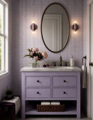 Lit up in this lavender-toned bathroom, the Thalia sconces add warmth and glow to an already charming space. The pastel marbling, brass hardware, and globe bulbs feel fresh and whimsical, making them a beautiful fit for a feminine powder room, a soft grandmillennial bath, or a playful bathroom with a delicate color story.