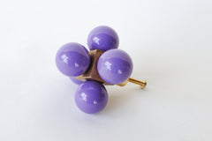 An Orchid Purple Oversized Ball Cube Knob by Sazerac Stitches, featuring four purple spheres mounted in a brass cube, designed as a decorative and modern drawer pull.