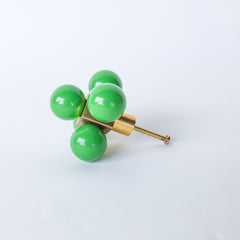 Add a pop of playful color to your space with the Oversized Ball Cube Knob by Sazerac Stitches. This unique drawer pull features a bold design with four vibrant spring green spheres set in a brass cube, creating a striking balance of modern and retro vibes. Perfect for upgrading your cabinets or drawers with a touch of personality and style.