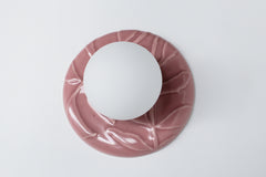 Angled overhead shot of pastel pink leaf-textured backplate with frosted globe bulb, whimsical feminine wall sconce for chinoiserie interiors.