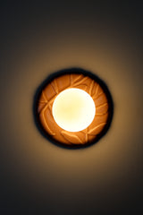 Installed pastel pink Leafy Sconce turned on with warm glow, frosted globe and glossy ceramic leaf relief backplate, cozy ambient wall lighting for a powder room, bedside reading nook, or chinoiserie inspired hallway.