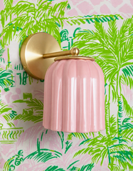 Sketch-style palm fronds cover this wallpaper in bright kelly green with pink accents, and the Marcella Sconce in Pastel Pink pulls out that secondary pink for a candy-bright, confident pop against all that green. A cheerful, preppy pairing for powder rooms and bathrooms that want tropical print with real color contrast rather than a tonal blend.