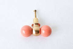 Peach and brass double gumball drawer pull, head-on view with mounting screw visible. A small colorful detail that suits furniture makeovers, colorful bathrooms, built-ins, kitchens, kids' spaces, and offices alike.