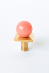 A round glossy peach knob set on a brass square backplate, turned at a slight diamond angle for a bit of geometry. A small, easy way to bring color into cabinetry or furniture without committing to a full paint job. Good for anyone building out a colorful kitchen, dresser, or vanity one detail at a time.