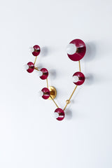 Pisces star sign wall light in deep black cherry red and brass, constellation style sconce with round powder coated steel discs and glowing white globe bulbs, modern sculptural statement fixture with mid century modern vibes and artsy maximalist energy, perfect for a pretty powder room, feminine bathroom lighting, bold eclectic home decor, colorful designer bathroom vanity sconce, astrology inspired wall fixture for personality filled interiors