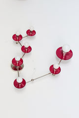 Pisces star sign wall light in deep black cherry red and chrome, constellation style sconce with round powder coated steel discs and glowing white globe bulbs, modern sculptural statement fixture with mid century modern vibes and artsy maximalist energy, perfect for a pretty powder room, feminine bathroom lighting, bold eclectic home decor, colorful designer bathroom vanity sconce, astrology inspired wall fixture for personality filled interiors