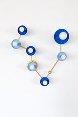 Pisces constellation wall sconce in Mediterranean blue and hydrangea blue with warm brass arms and details, featuring powder-coated steel disc shades and globe bulbs in a star-map inspired layout; bold celestial lighting for a bathroom vanity, powder room, entryway, or bedroom, perfect for eclectic and maximalist interiors, mid century modern style homes, coastal-inspired blues, and anyone who wants a zodiac light fixture that is playful and not basic.