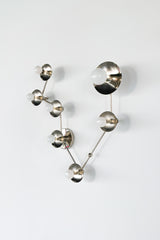 Angled side view of a Pisces star sign sconce in chrome, showing the dimensional branching arms and round metal disc details behind each white globe bulb; contemporary constellation wall fixture that reads like functional wall art, ideal for eclectic home decor, mid century modern lighting fans, bold bathroom lighting over a mirror, moody modern bedroom accent light, or a unique zodiac inspired statement piece.