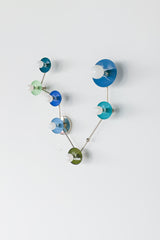 Pisces zodiac constellation wall sconce with powder-coated steel discs in mixed blue and green tones (teal, mint, denim, hydrangea blue, Mediterranean blue, olive) on polished chrome arms, finished with white globe bulbs; artistic constellation-style lighting for a maximalist bathroom vanity, playful kids room, eclectic hallway, or modern coastal interior, mid century modern statement wall light with bold color blocking.