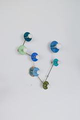 Pisces zodiac constellation wall sconce with powder-coated steel discs in mixed blue and green tones (teal, mint, denim, hydrangea blue, Mediterranean blue, olive) on polished chrome arms, finished with white globe bulbs; artistic constellation-style lighting for a maximalist bathroom vanity, playful kids room, eclectic hallway, or modern coastal interior, mid century modern statement wall light with bold color blocking.
