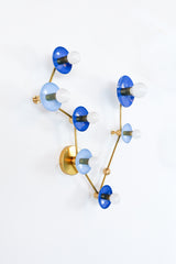 Pisces constellation wall sconce in Mediterranean blue and hydrangea blue with warm brass arms and details, featuring powder-coated steel disc shades and globe bulbs in a star-map inspired layout; bold celestial lighting for a bathroom vanity, powder room, entryway, or bedroom, perfect for eclectic and maximalist interiors, mid century modern style homes, coastal-inspired blues, and anyone who wants a zodiac light fixture that is playful and not basic.