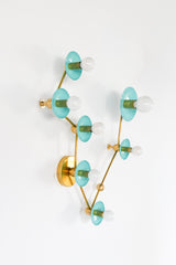 Angled view of Pisces constellation light fixture in Poolside blue and brass, with sculptural branching arms, powder-coated steel disc backplates, and round globe bulbs; statement wall lighting with mid century modern vibe for an artful bathroom sconce over a mirror, fun powder room lighting, coastal color pop decor, and bold maximalist style.