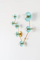 Angled view of Pisces constellation light fixture in Poolside blue and brass, with sculptural branching arms, powder-coated steel disc backplates, and round globe bulbs; statement wall lighting with mid century modern vibe for an artful bathroom sconce over a mirror, fun powder room lighting, coastal color pop decor, and bold maximalist style.