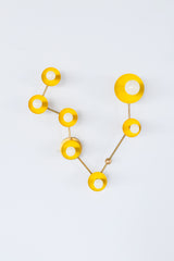 Pisces zodiac wall sconce in glossy sunshine yellow powder coated steel with warm brass arms, constellation inspired star sign light fixture with sculptural discs and white globe bulbs, bold modern lighting for a maximalist bathroom vanity, whimsical powder room, colorful entryway, or eclectic bedroom wall lighting